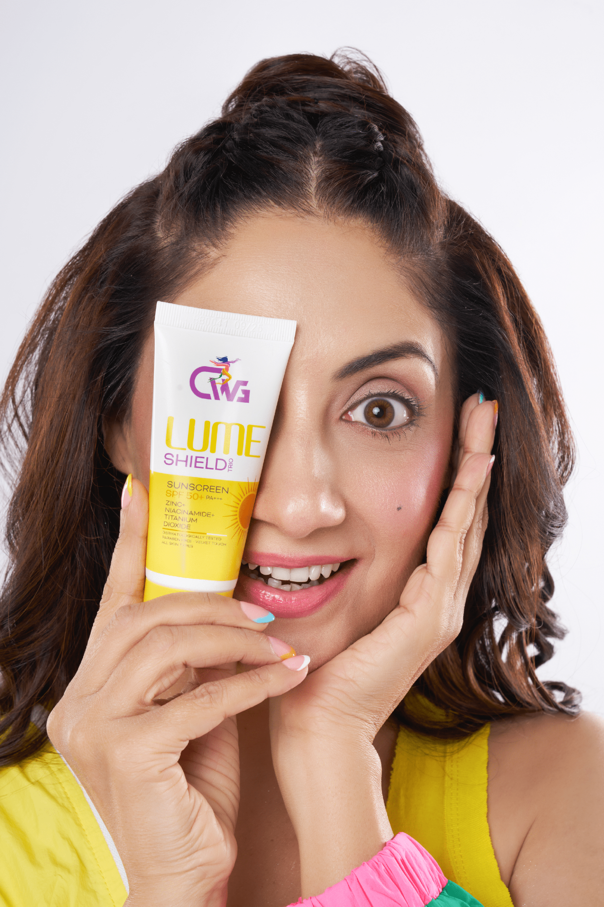 CWG lume shield trio sunscreen Test held by a smiling woman, showcasing its bright yellow packaging.